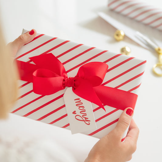 Red and white stripe wrapped gift with merry heart tag and red bow
