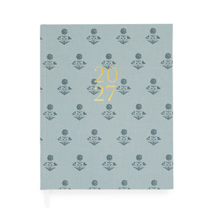 A dusty blue fabric planner with dark blue floral pattern and '2027' stamped on the cover in gold foil with two white ribbon markers
