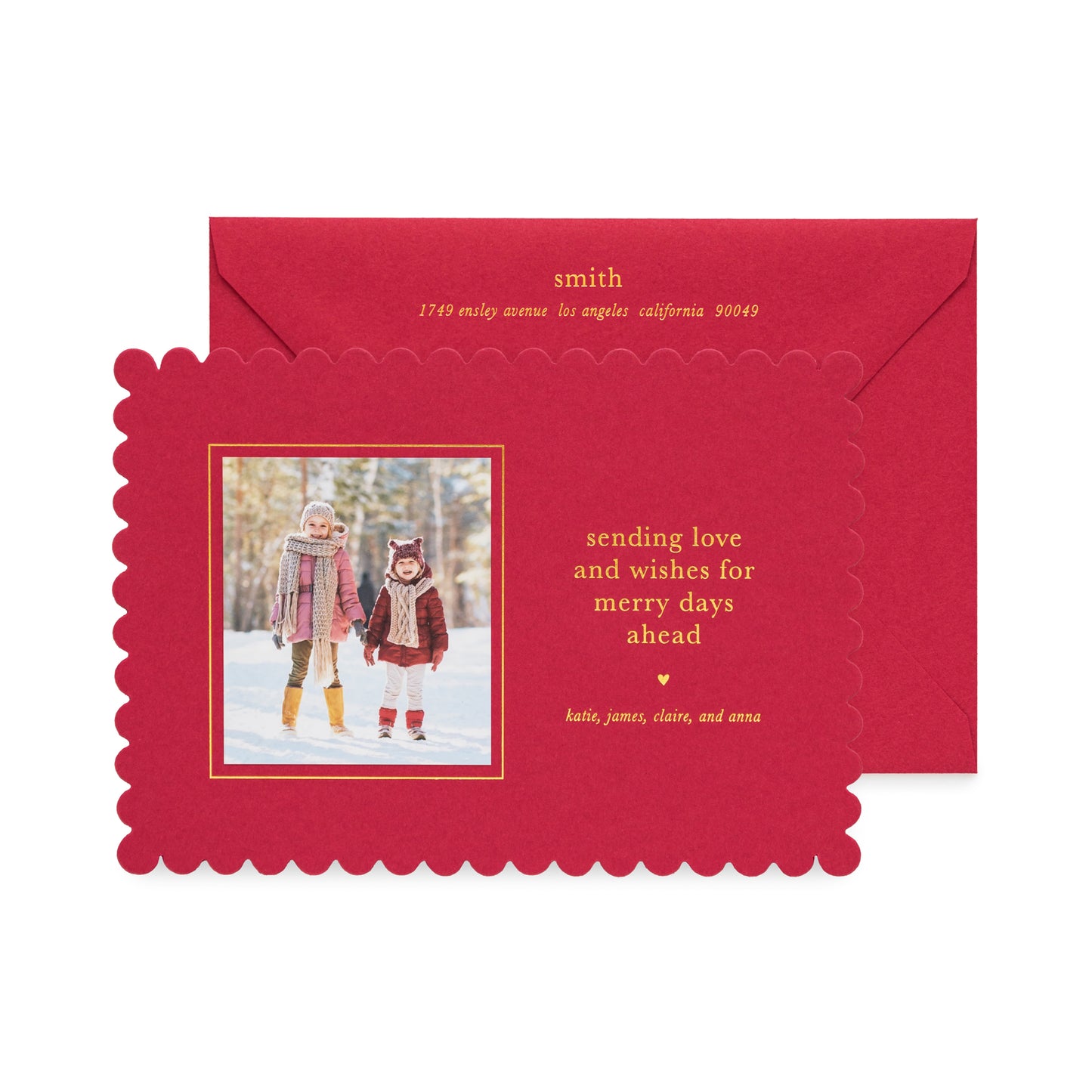 Red scalloped custom holiday photo card with a photo of two kids in the snow with gold foil 'sending love and wishes for merry days ahead' paired with a red envelope with gold foil return address