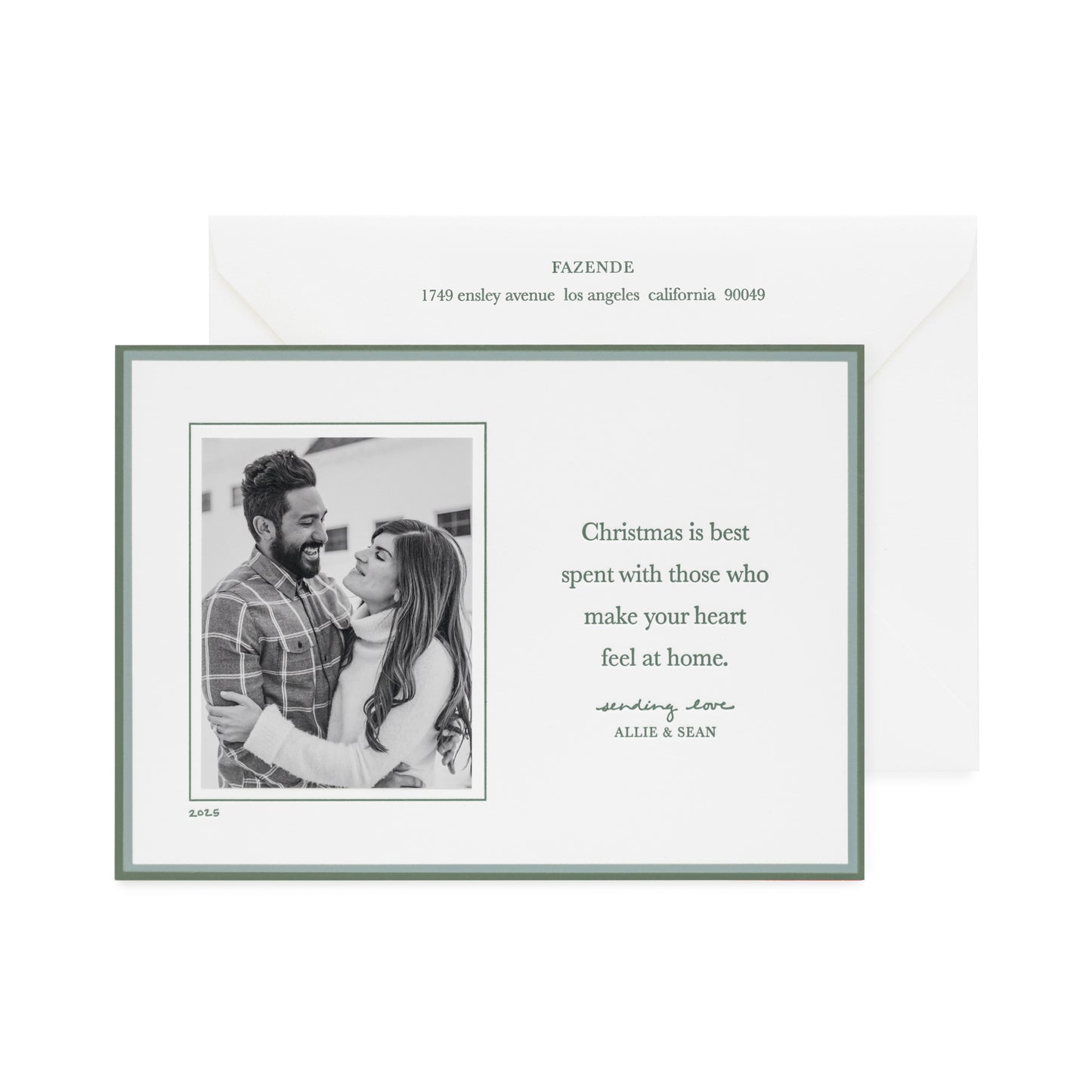 Custom holiday photo card with a black and white photo with a double green border on a white card with green letterpress ink messaging 'christmas is best spent with those that make your heart feel at home' paired with a white envelope with matching green ink with address