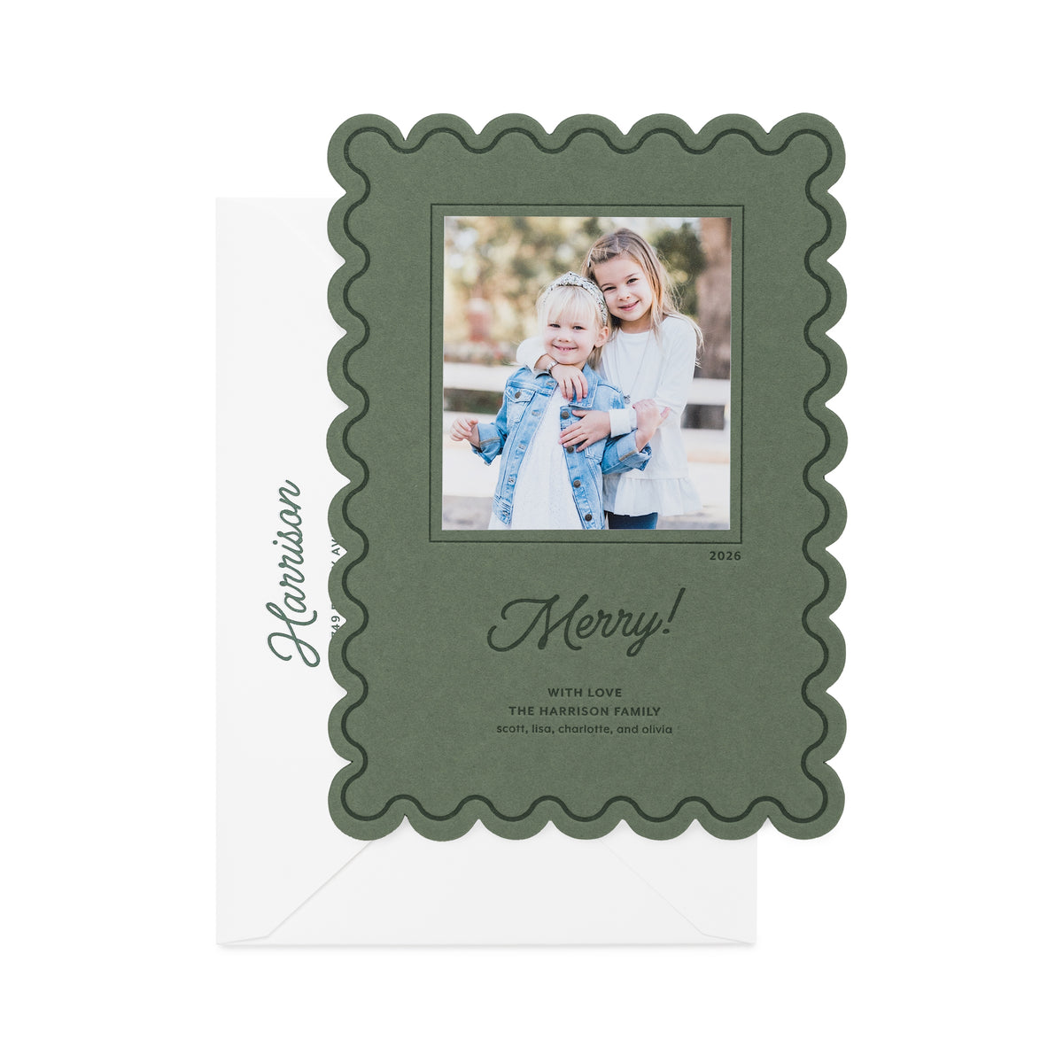 A rosemary green holiday photo card with a scalloped border, featuring a custom family photo of two girls, the text 'Happy Holidays' in script in dark green ink, and the name 'Harrison' printed on the white envelope.