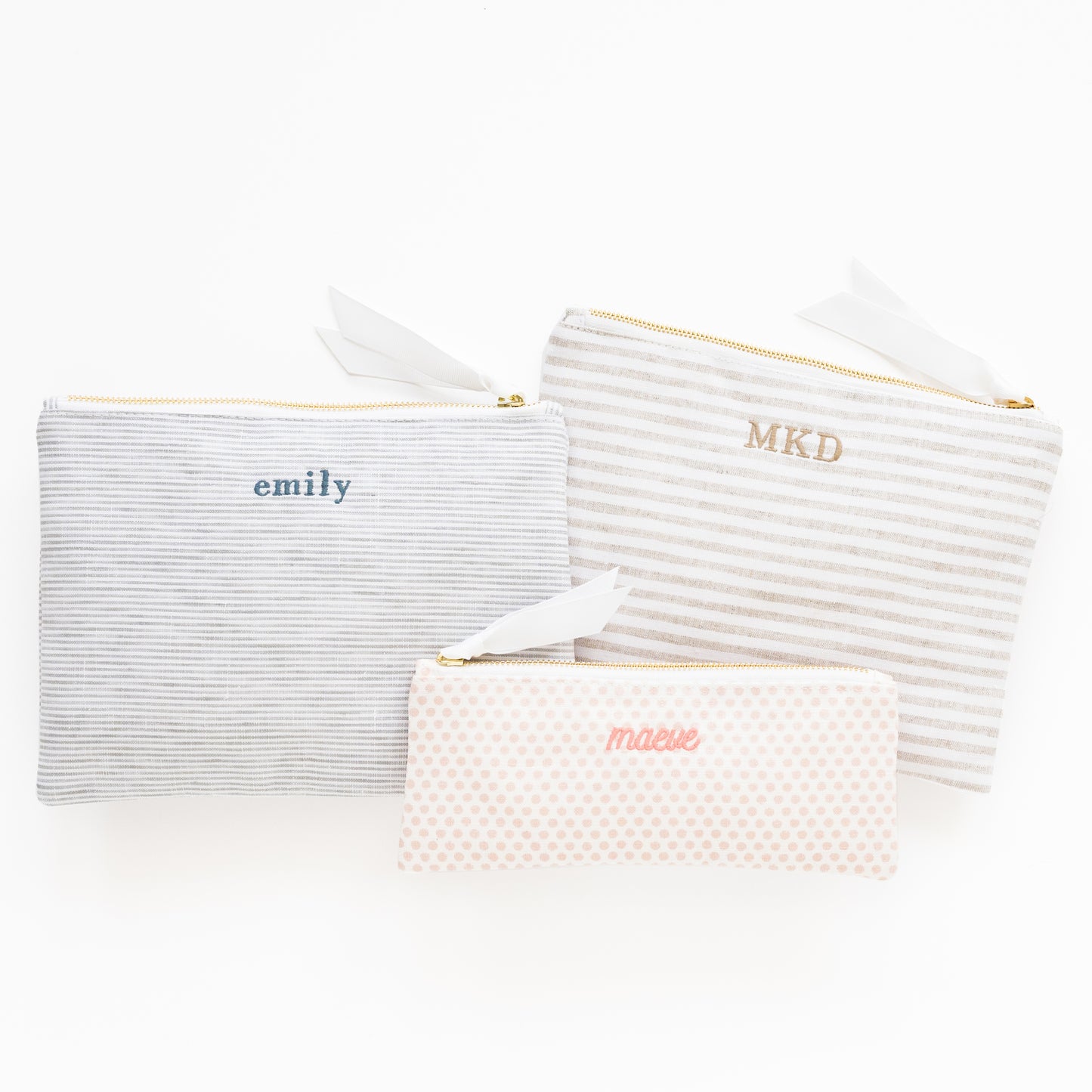 Striped and dot fabric pouches in various colors and sizes with names embroidered on them