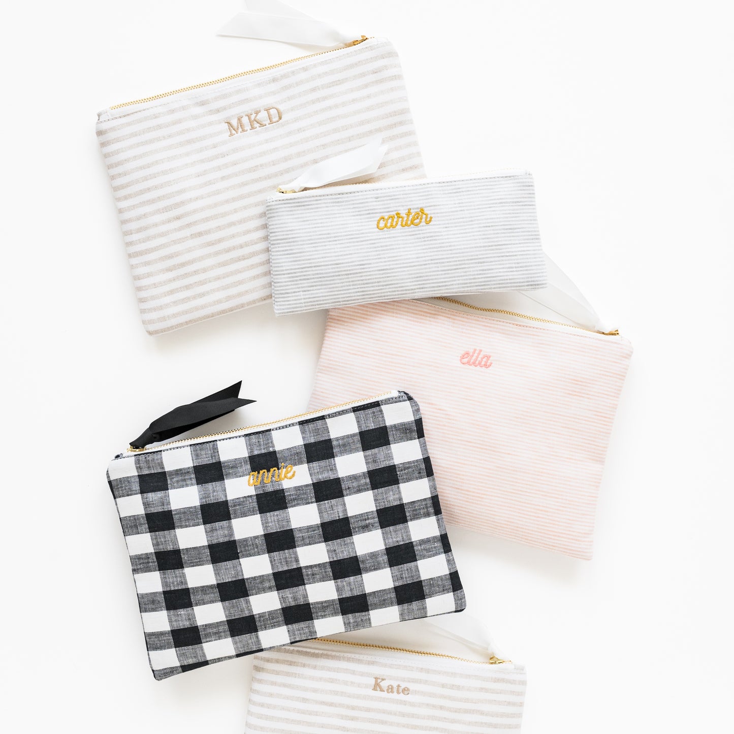 Assorted fabric pouches in stripe and check patterns with embroidered names and initials