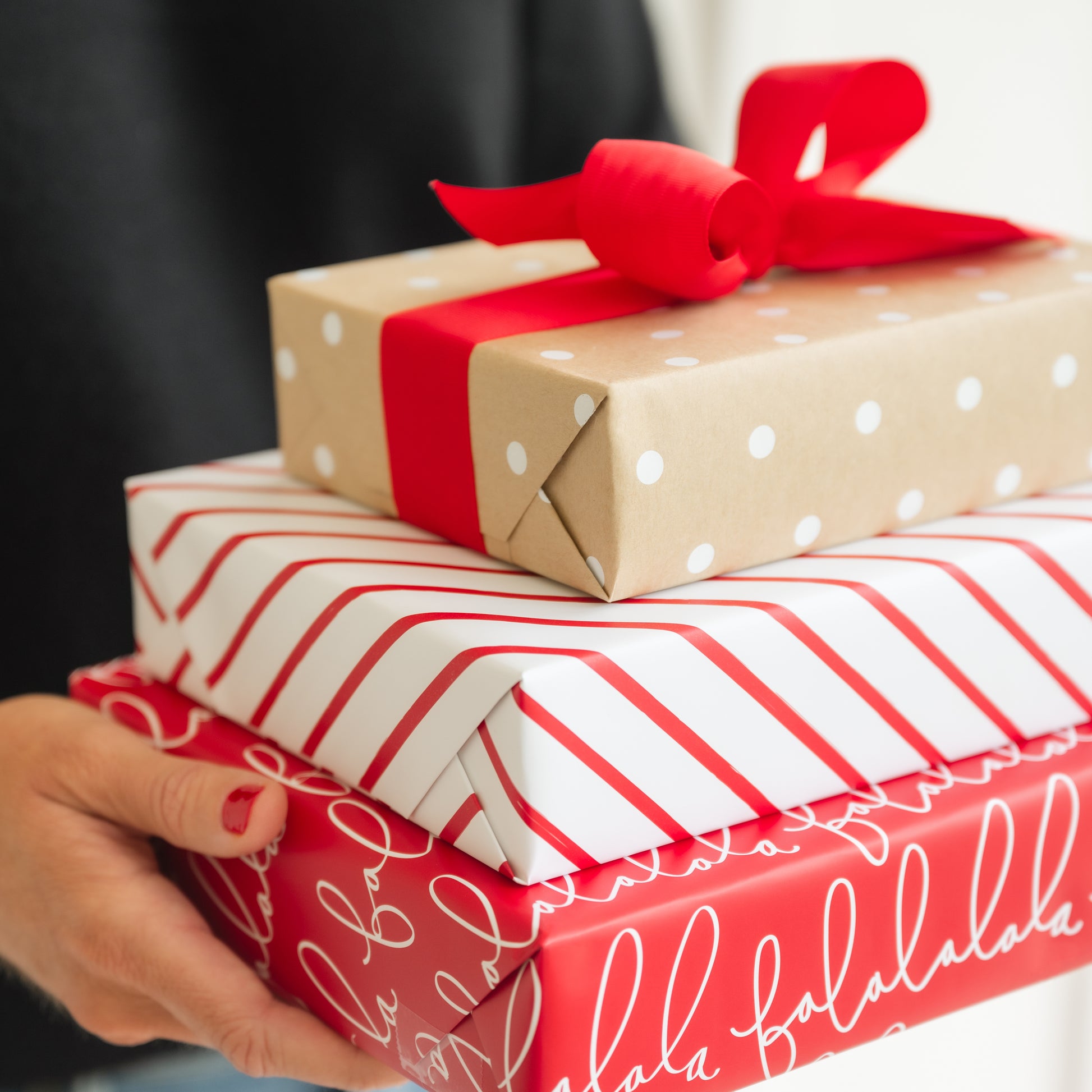 Stack of wrapped holiday christmas gifts in hand