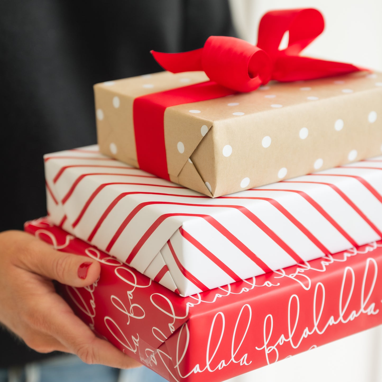 Stack of holiday wrapped gifts with red falalala wrap