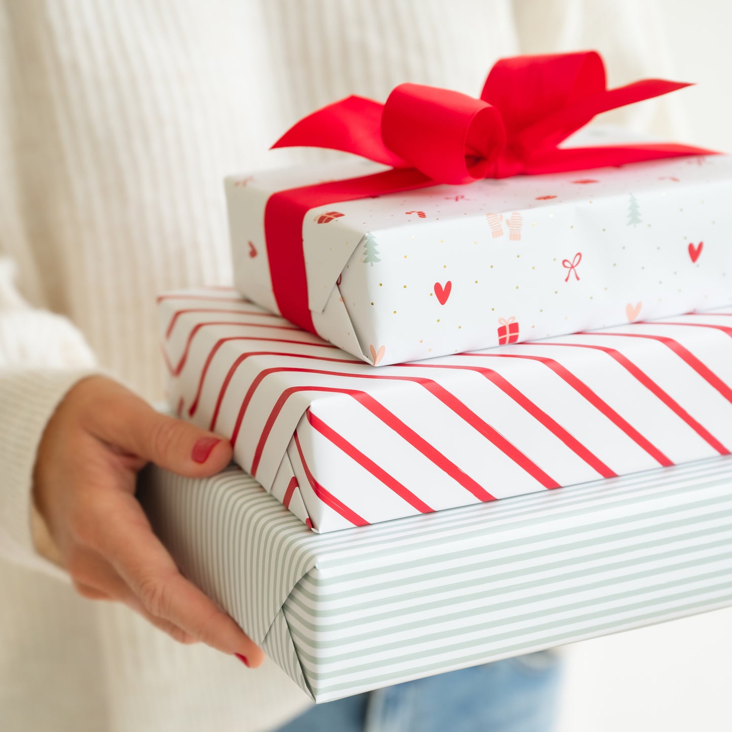Stack of wrapped holiday kits in hand in red white and mint green