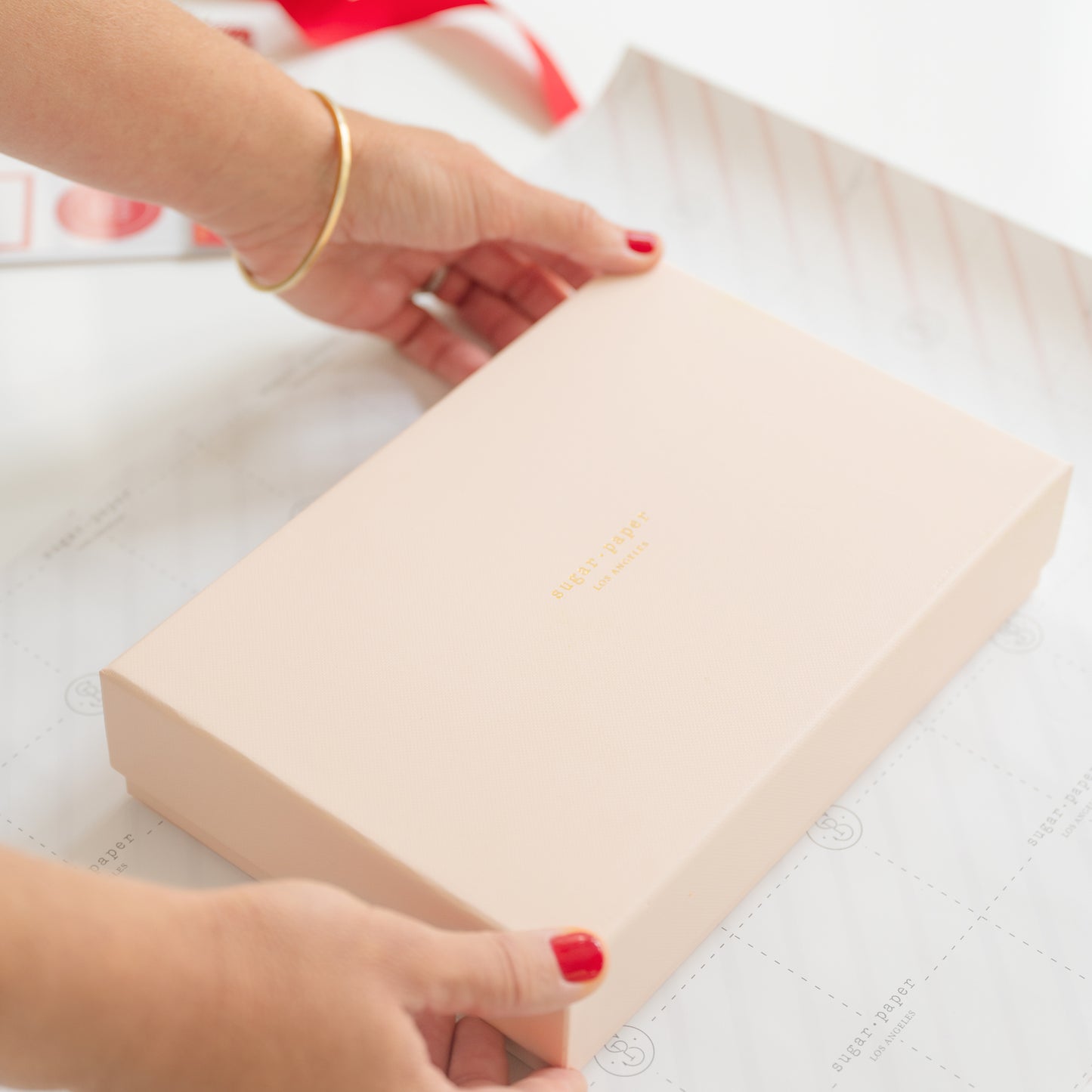 Top of pink sugar paper gift box on white and red stripe wrapping paper about to be wrapped