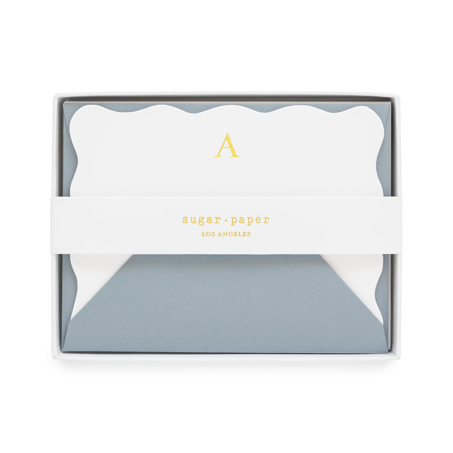 White bordered scallop with gold foil initial 'a' paired with a slate blue envelope in a white box with a white belly band with a 'sugar paper los angeles' gold foil logo