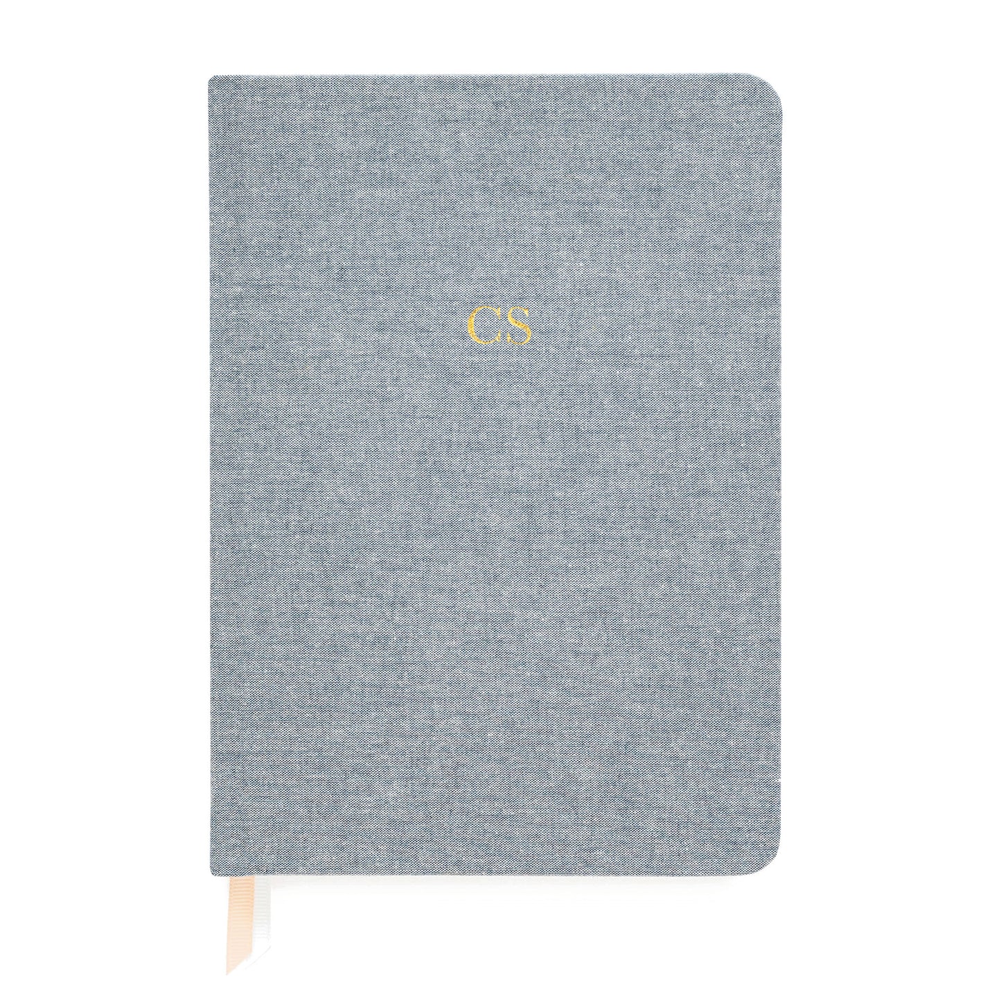 A blue fabric journal with a monogram 'CS' embossed on the cover.