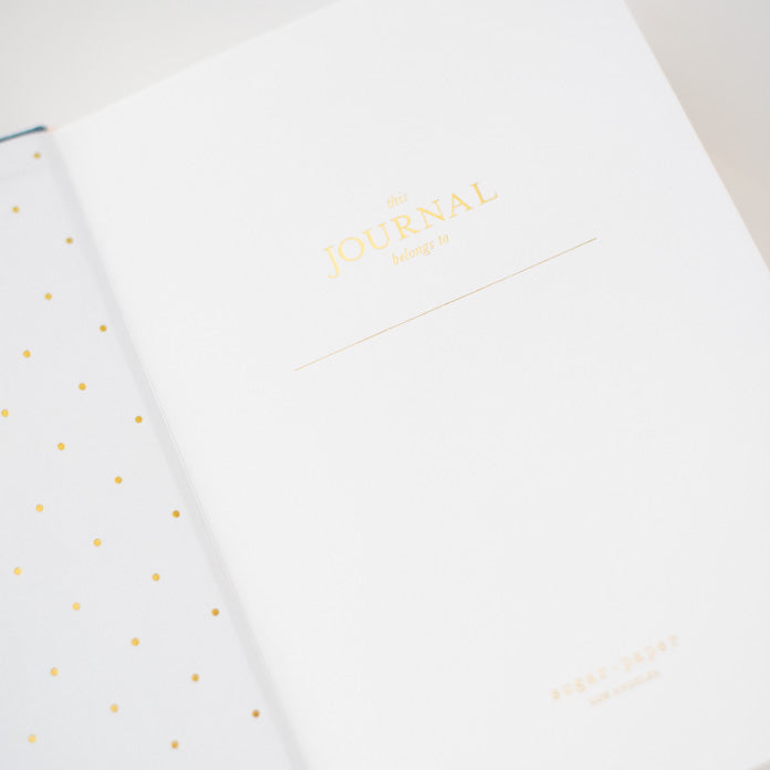 interior page of fabric journal printed in gold foil with this journal belongs to