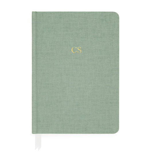Sage green fabric journal with white ribbon markers foil stamped with gold initials