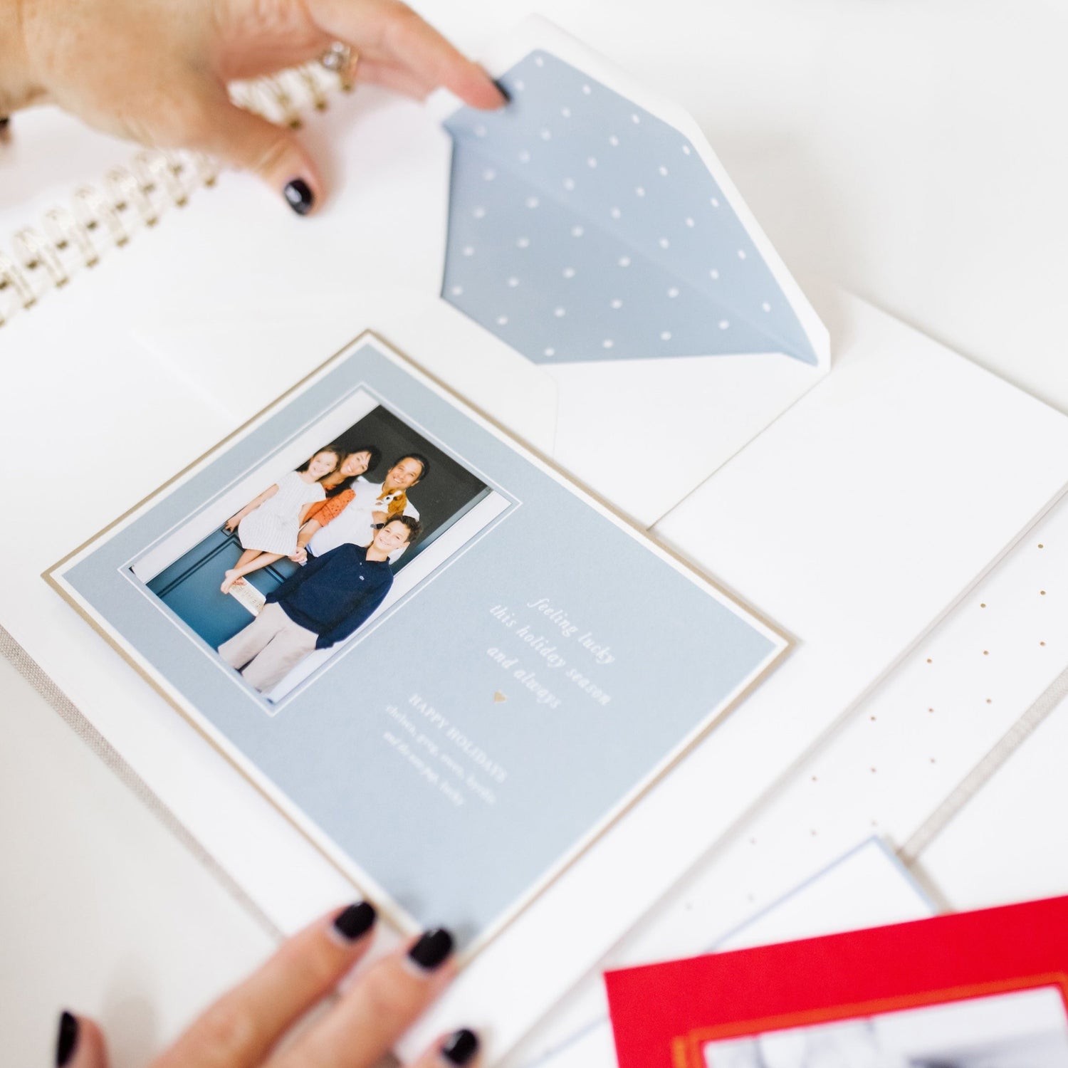 holiday card book open with a blue and white holiday family photo card being pasted onto the page