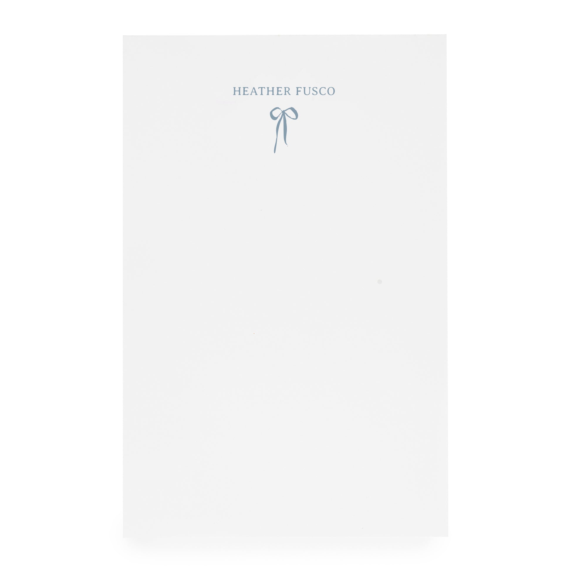 White notepad with ribbon bow and "heather fusco" in blue ink