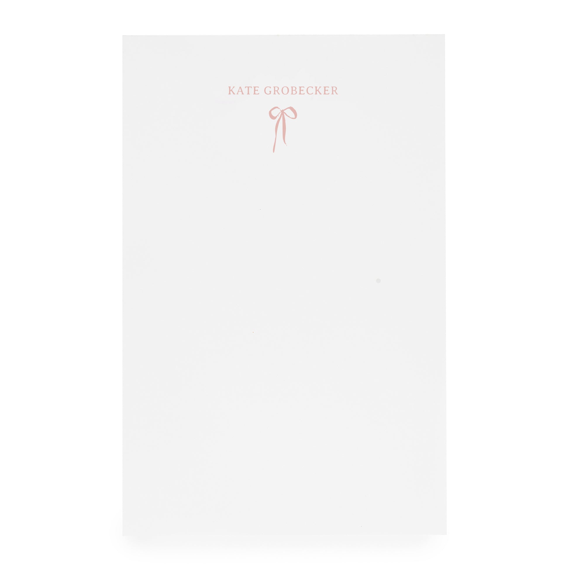 White notepad with pink bow and "kate grobecker" in pink