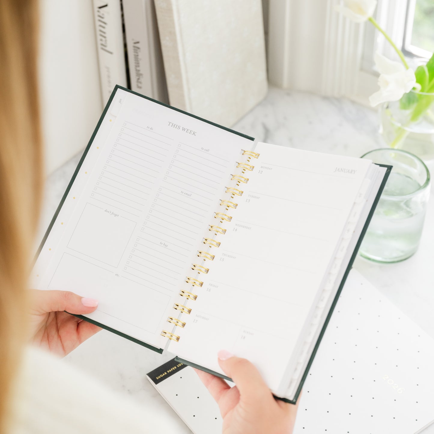 Person holding a small spiral planner open to this week page