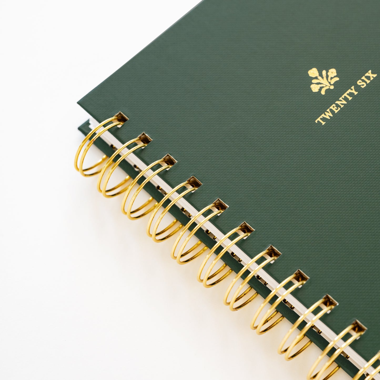 Close up of small green spiral planner with 'twenty six' in gold foil on cover and gold spiral binding
