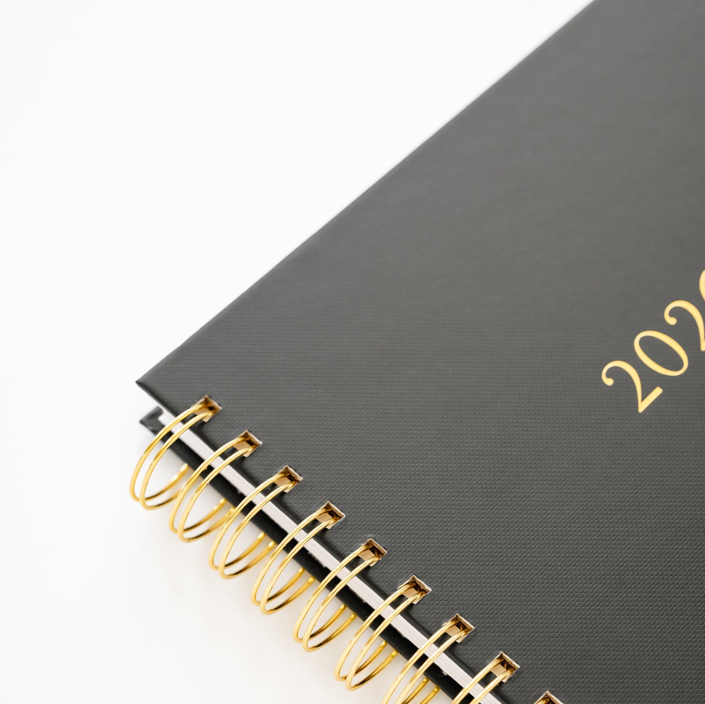 Closeup of the gold spiral binding of the black with '2026' printed on the cover