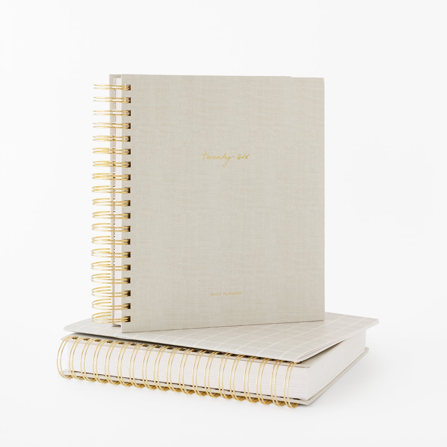 Two beige spiral planners with gold wire binding stackced