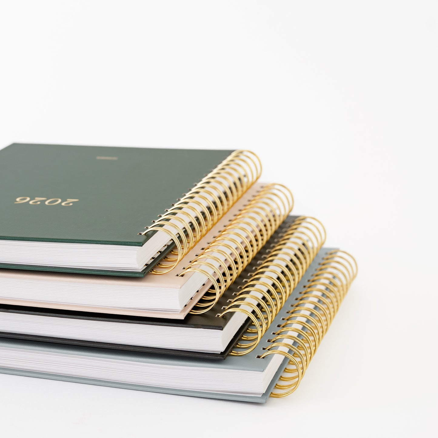 Stack of spiral-bound planner with gold binding with 2026 on cover