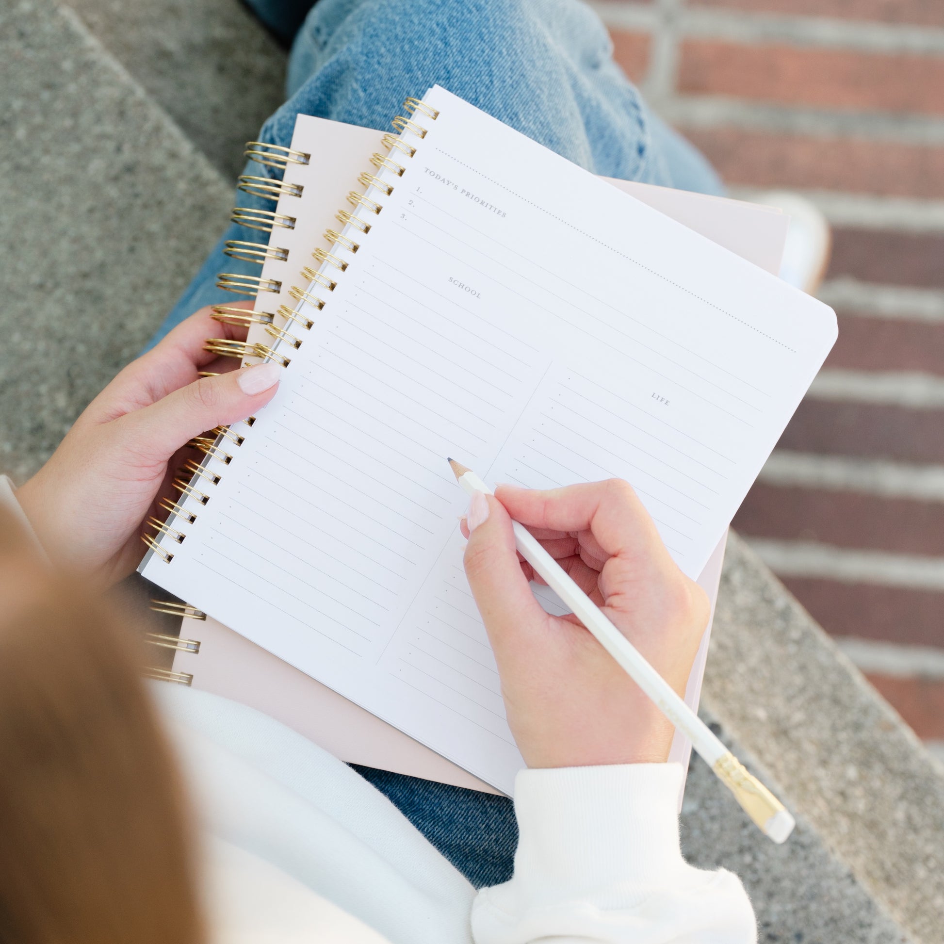 Person holding a spiral bound school/life notebook showing interior with today's priorities, school and life task lists