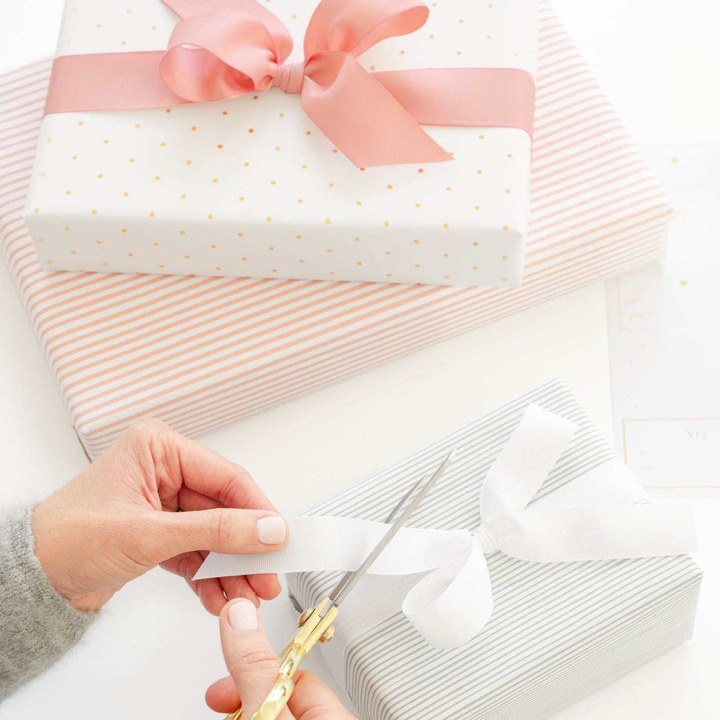 woman trimming ribbon on a gift with other wrapped gifts