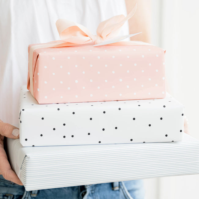 Woman holding a stack of wrapped presents in different wrapping paper patterns