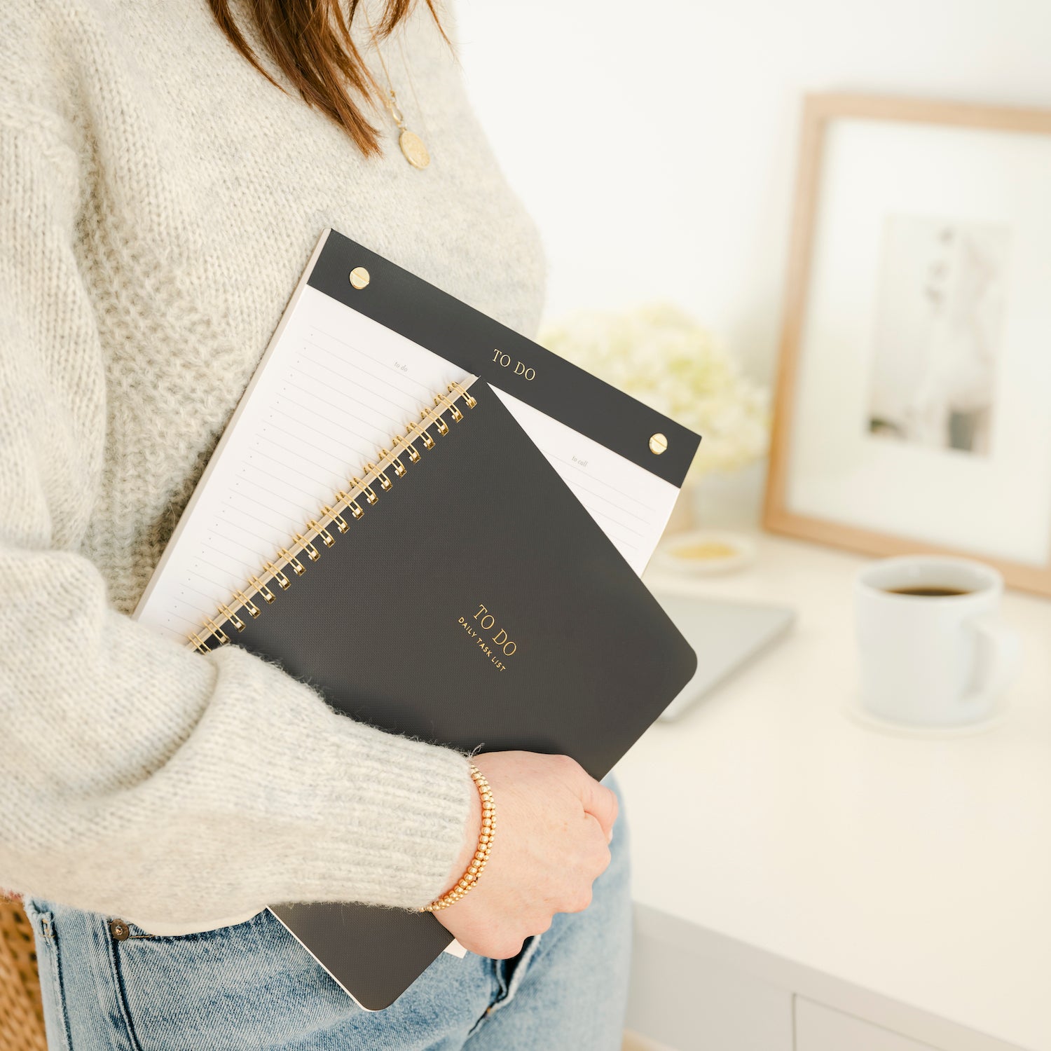Stack of guided to do spiral notebook and to do notepad in black and gold colors