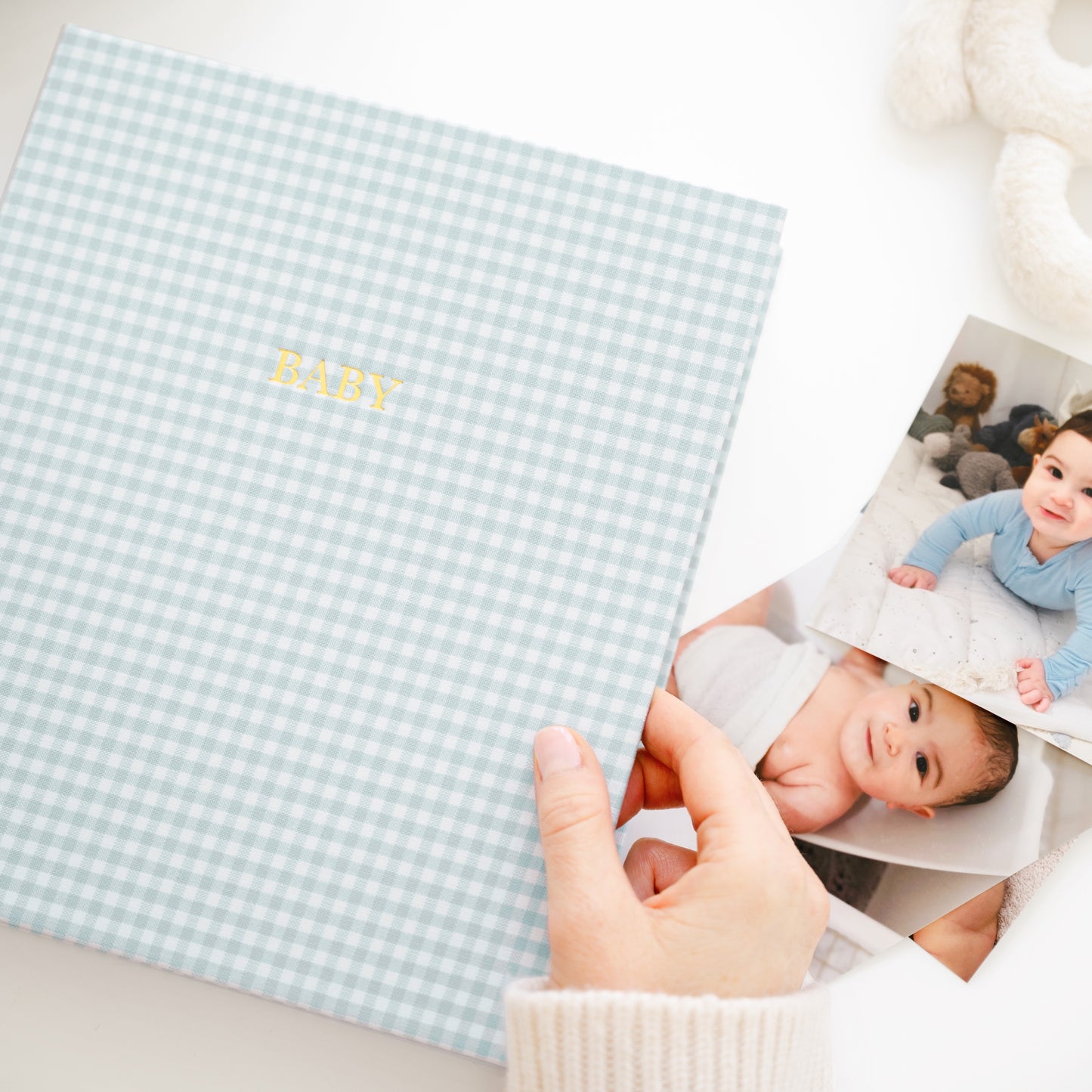 blue gingham baby book on a desk with photos