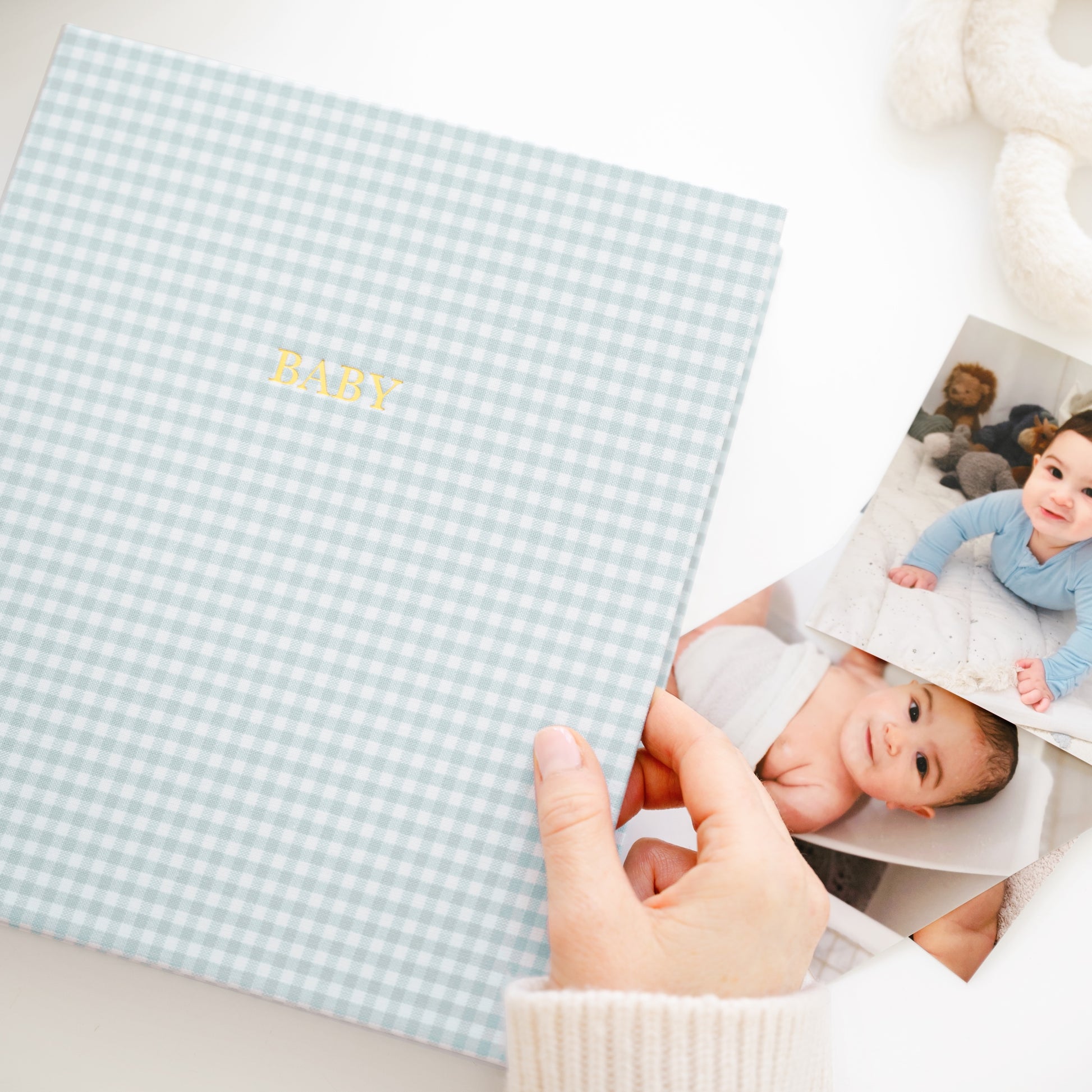 blue gingham baby book on a desk with photos