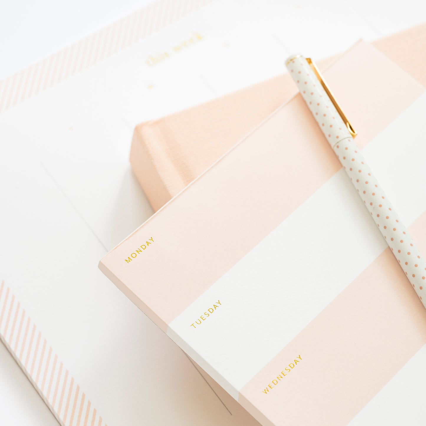 Pink notepads stacked with pink journal and pen