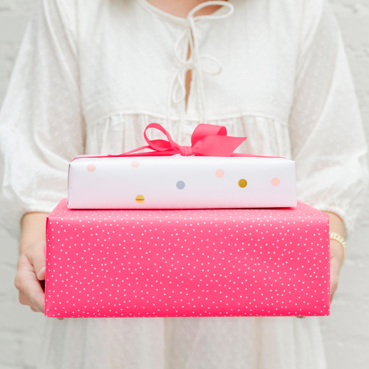 Stack of sugar paper and target wrapped gifts in neon pink and a bright colored polka dot