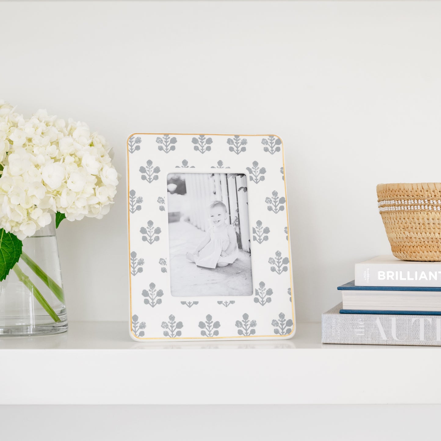 slate grey floral patterned ceramic frame with a photo of a little girl on a shelf