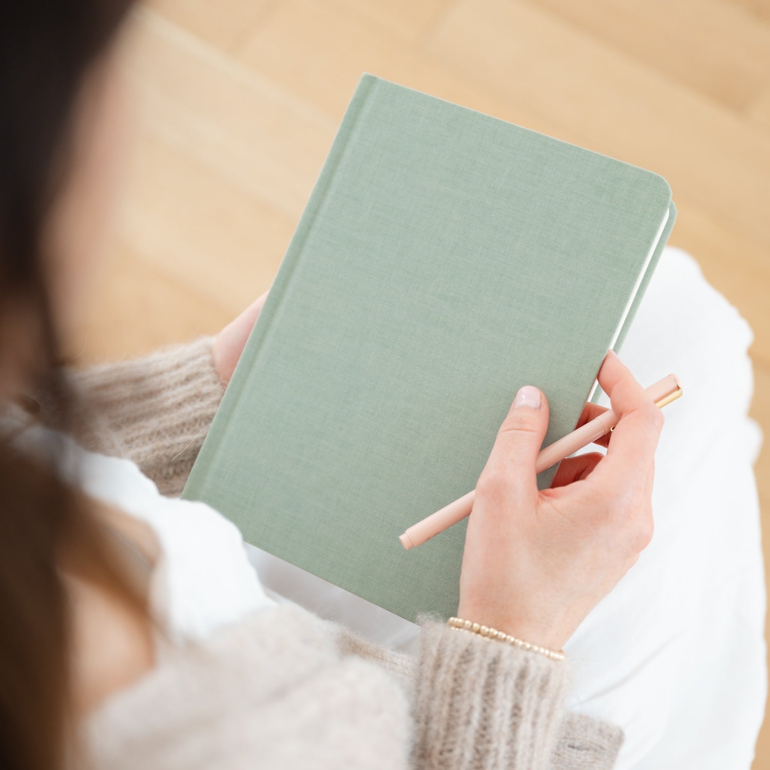 Sage green journal in hand with pink pen