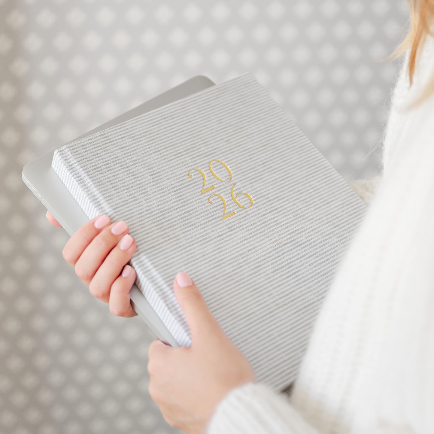 Grey stripe fabric planner with '26' in gold foil on the cover in hands