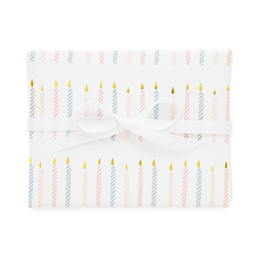 birthday candle gift wrap printed with a colorful candle pattern in pink and blue with gold foil tied with a white ribbon