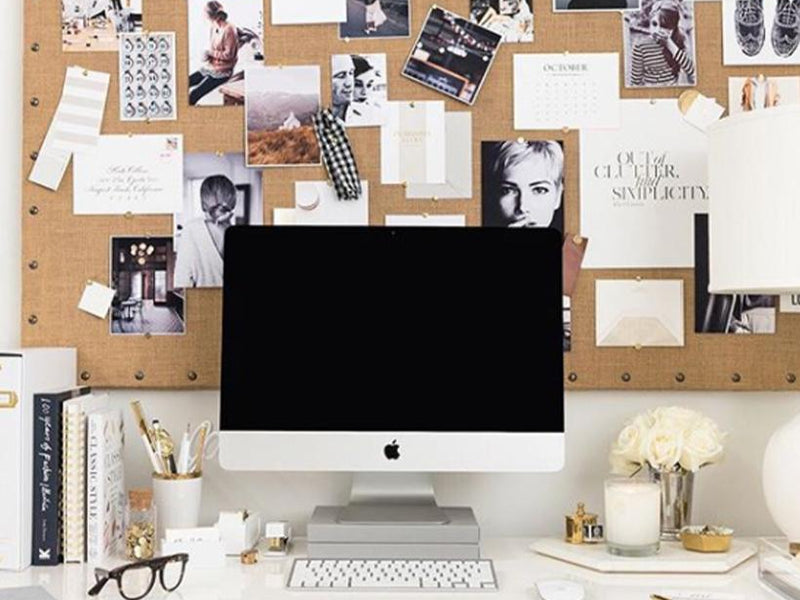 Inspiration board behind computer on styled desk