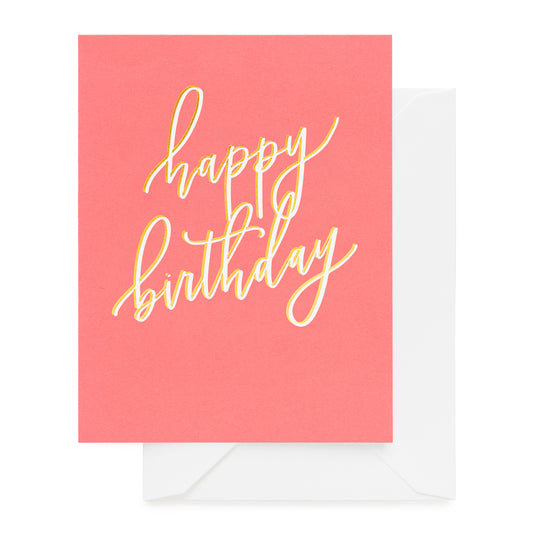 Happy birthday printed in white and gold foil on neon coral paper