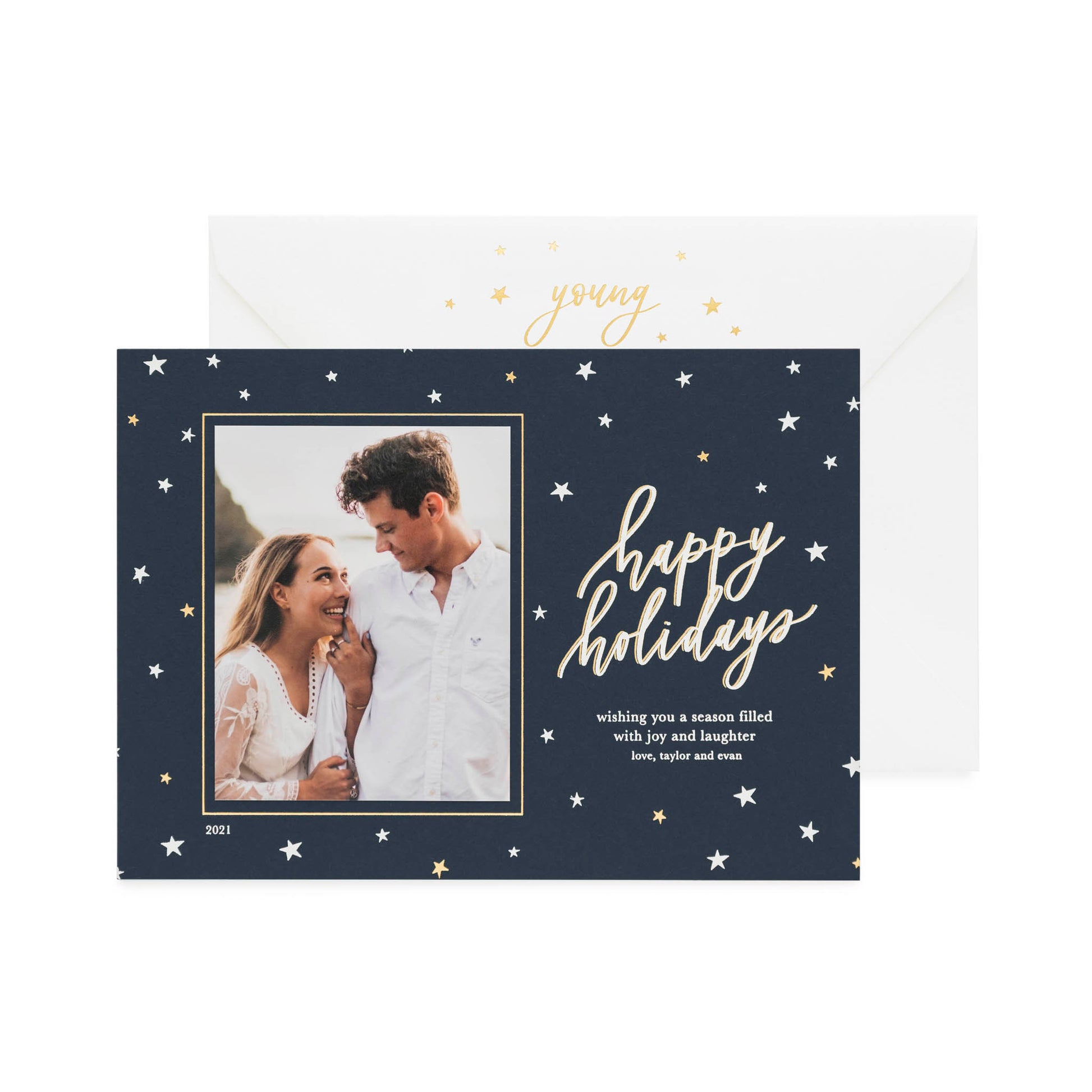 A navy custom holiday photo card featuring a picture of a couple with a star decoration pattern, with the text 'Happy Holidays' and a seasonal greeting in gold and white foil paired with a white envelope