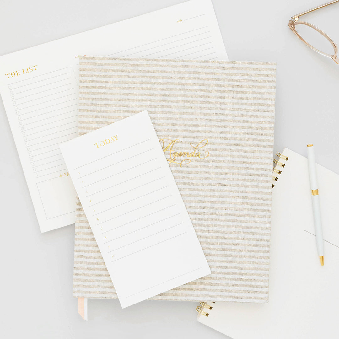 Stacked note pads and agenda in white and gold