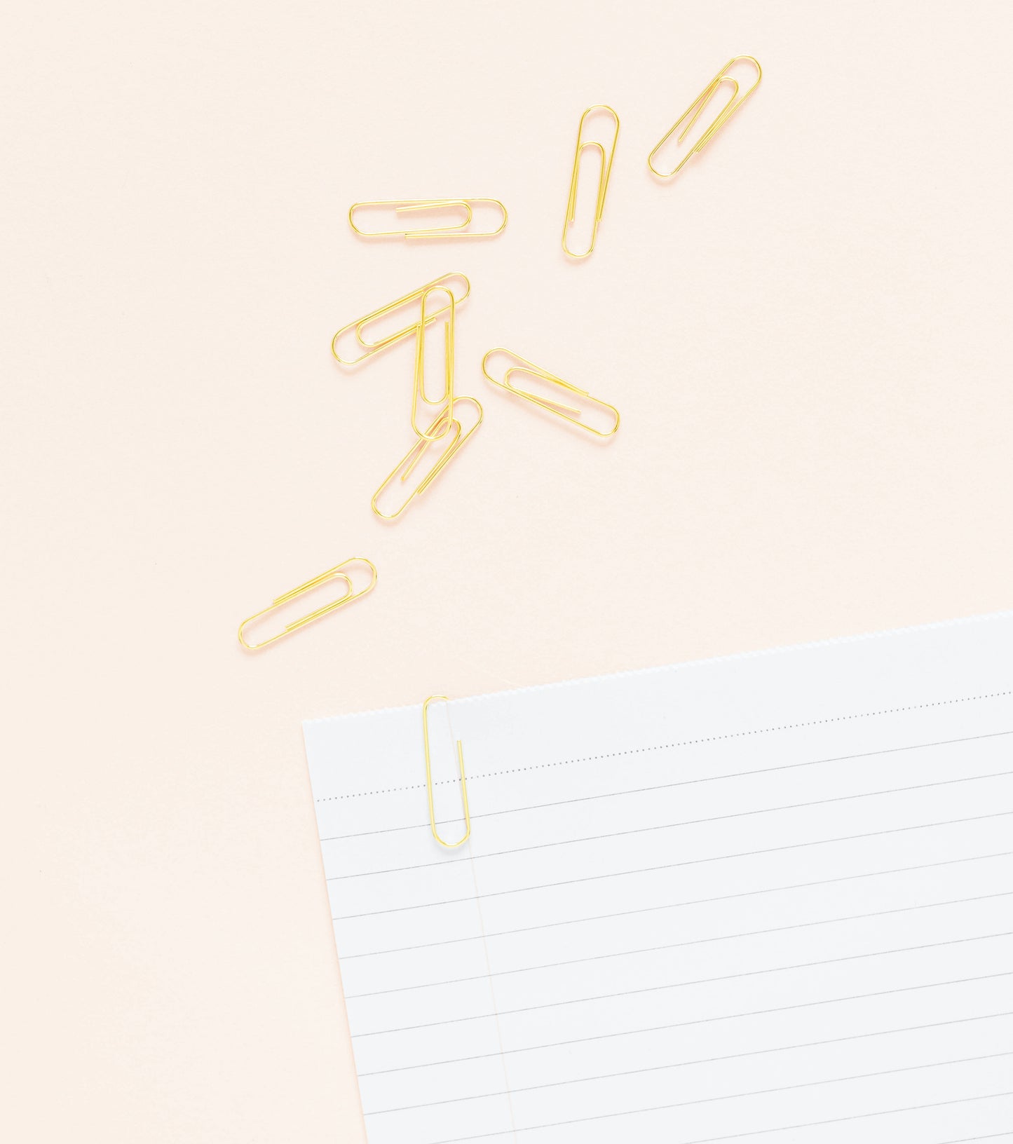 Gold paper clips on paper