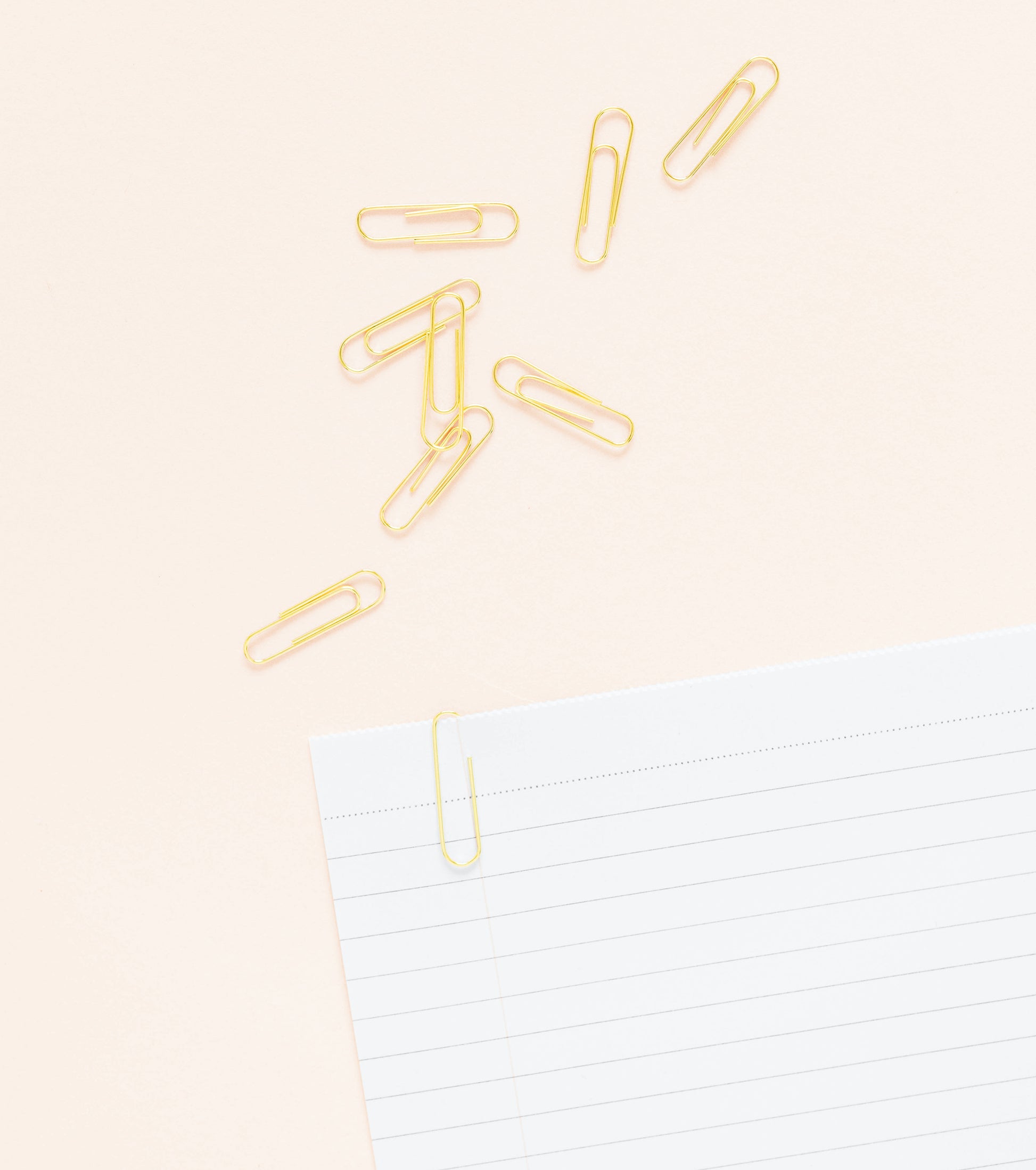 Gold paper clips on paper