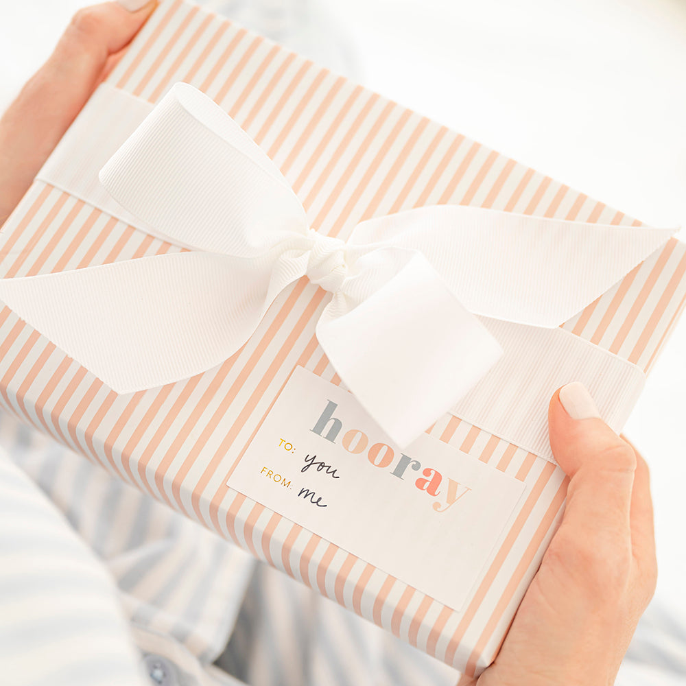 pink and white striped wrapped gift with white bow and hooray birthday sticker written with "to: you from: me"