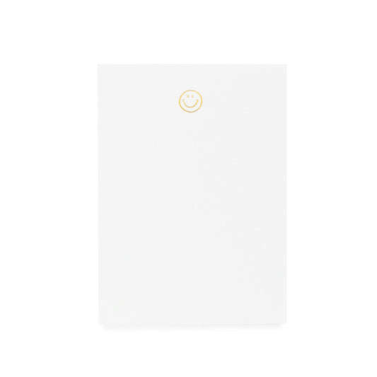 White notepad printed with gold foil smiley