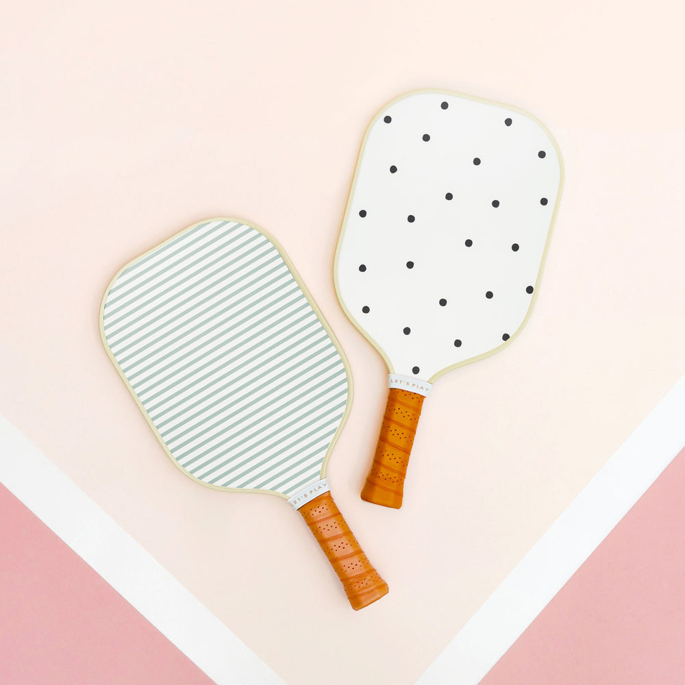 green stripe and black polka dot pickleball paddles on pink background