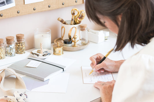 Sugar Paper founder Chelsea writing a note at her desk on her custom stationery