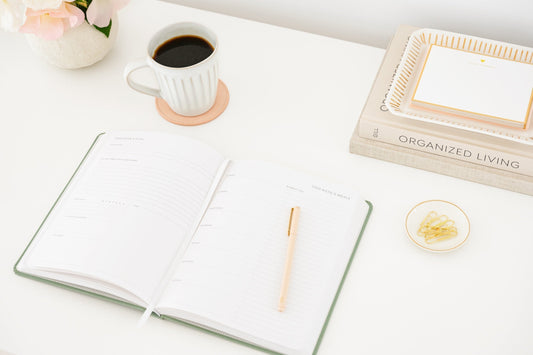 Open undated planner on desk with stationery and coffee cup