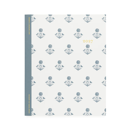 A white flat monthly planner with a dusty blue floral pattern with '2027' stamped on cover in gold foil with a dusty blue tape binding