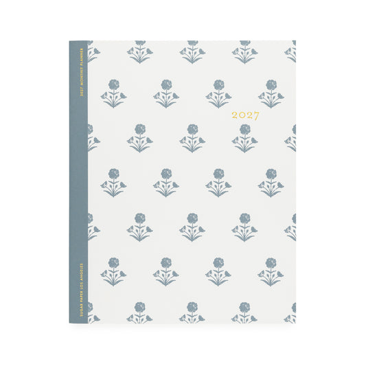 A white flat monthly planner with a dusty blue floral pattern with '2027' stamped on cover in gold foil with a dusty blue tape binding