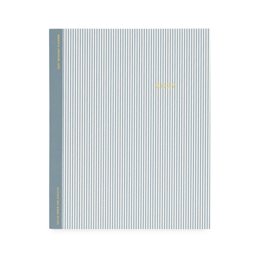 A flat monthly planner with a blue pinstripe pattern with '2027' stamped on cover in gold foil with a dusty blue tape binding