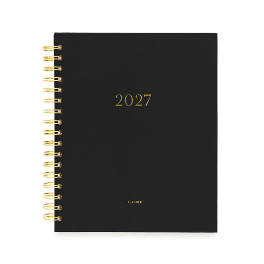 A black 2027 spiral-bound planner with gold foil lettering and a gold wire binding